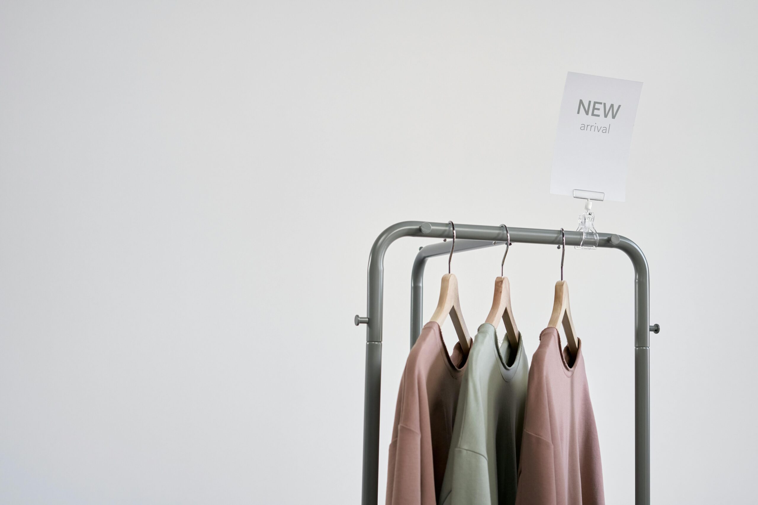 Stylish clothing on a rack with 'New Arrival' sign against a white wall.